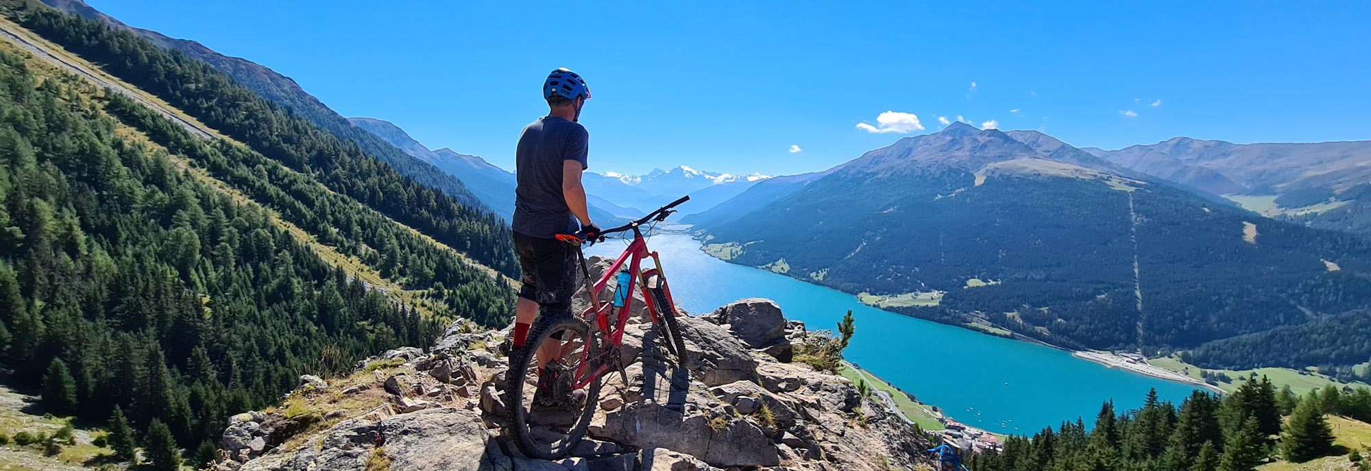 man standing on rocky mountain with bike